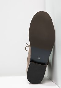 Beige Wildlederschuh mit Schnürung und schwarzem Gummisohle, auf der Unterseite mit der Größe '37' gekennzeichnet. Mit einer abgerundeten Zehenpartie und leicht strukturiertem Obermaterial.