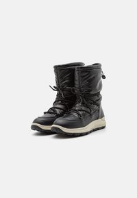 Botas de invierno negras aisladas con suelas gruesas beige, parte superior acolchada y cordones negros atados en la parte delantera y trasera para un ajuste ajustable.