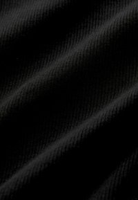 Black ribbed fabric displaying a soft texture with a slight sheen, featuring consistent lines and curves indicating drape and form.