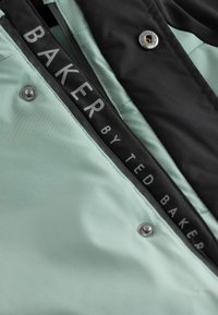 Jasná zelená a čierna bunda so zipsom, kovovými cvokmi a značkovou vnútornou nálepkou "BAKER BY TED BAKER."
