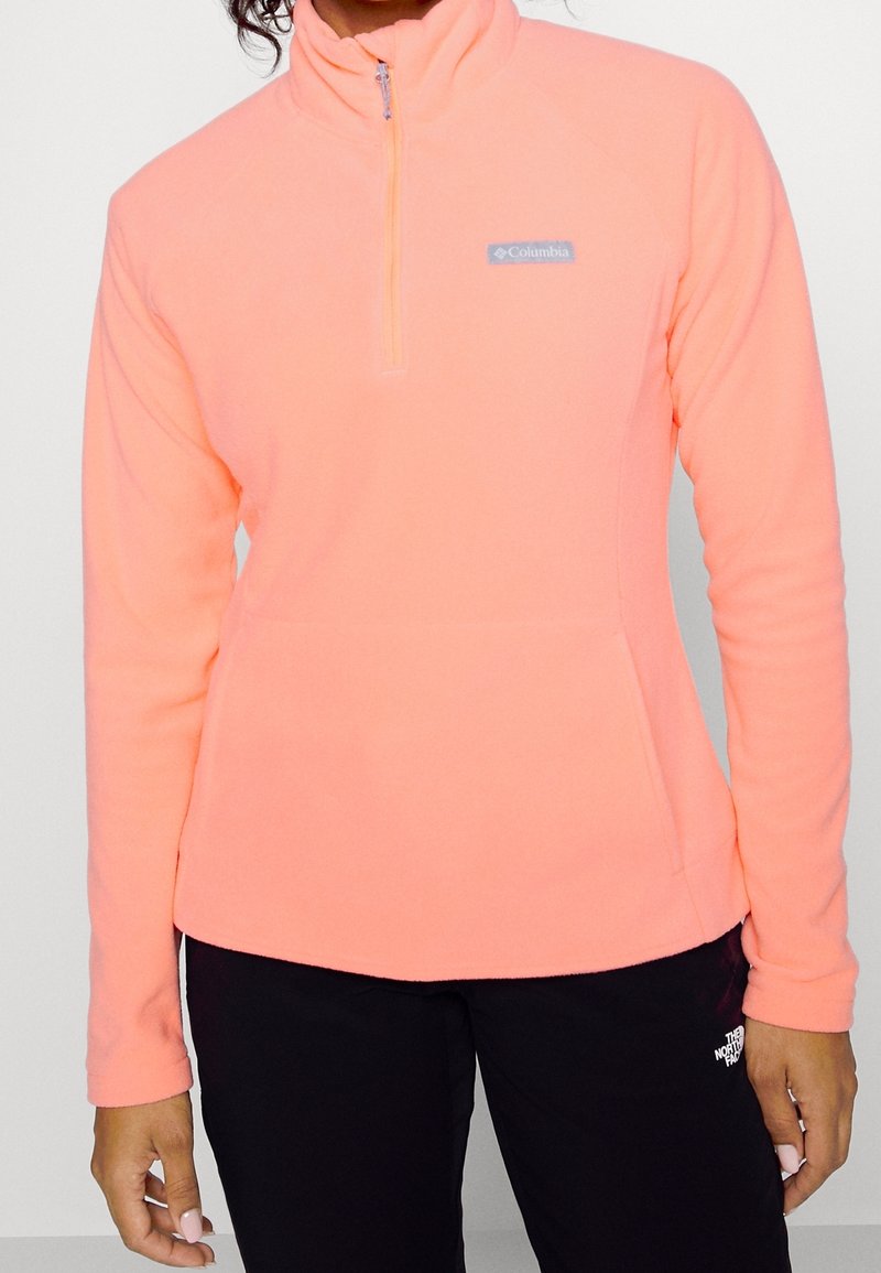Neonpinkki fleece-pulloveri, jossa on puolivetoketjullinen kaulus, pieni Columbia-logo vasemmalla rinnalla ja pitkät hihat.