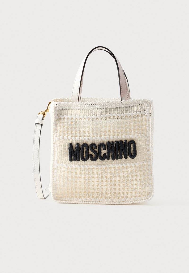 Λευκή υφαντή τσάντα Moschino tote με μαύρο λογότυπο, κοντές λαβές και αποσπώμενο ιμάντα ώμου σε μονόχρωμο φόντο.