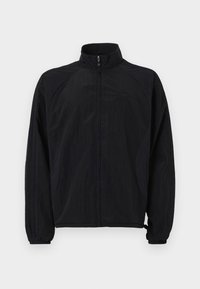 Chaqueta ligera negra con cuello alto, cierre de cremallera y puños elásticos. Fabricada con un tejido texturizado con un sutil diseño de paneles.