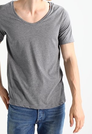 Graues T-Shirt mit kurzen Ärmeln und Rundhalsausschnitt, hergestellt aus weichem Stoff, kombiniert mit blauen Jeans aus Denim. Minimalistisches Design, keine sichtbaren Muster.