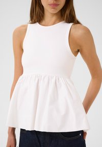 Top senza maniche bianco con un corpetto aderente e orlo a peplum arricciato. Realizzato in un tessuto morbido con una lucentezza sottile.