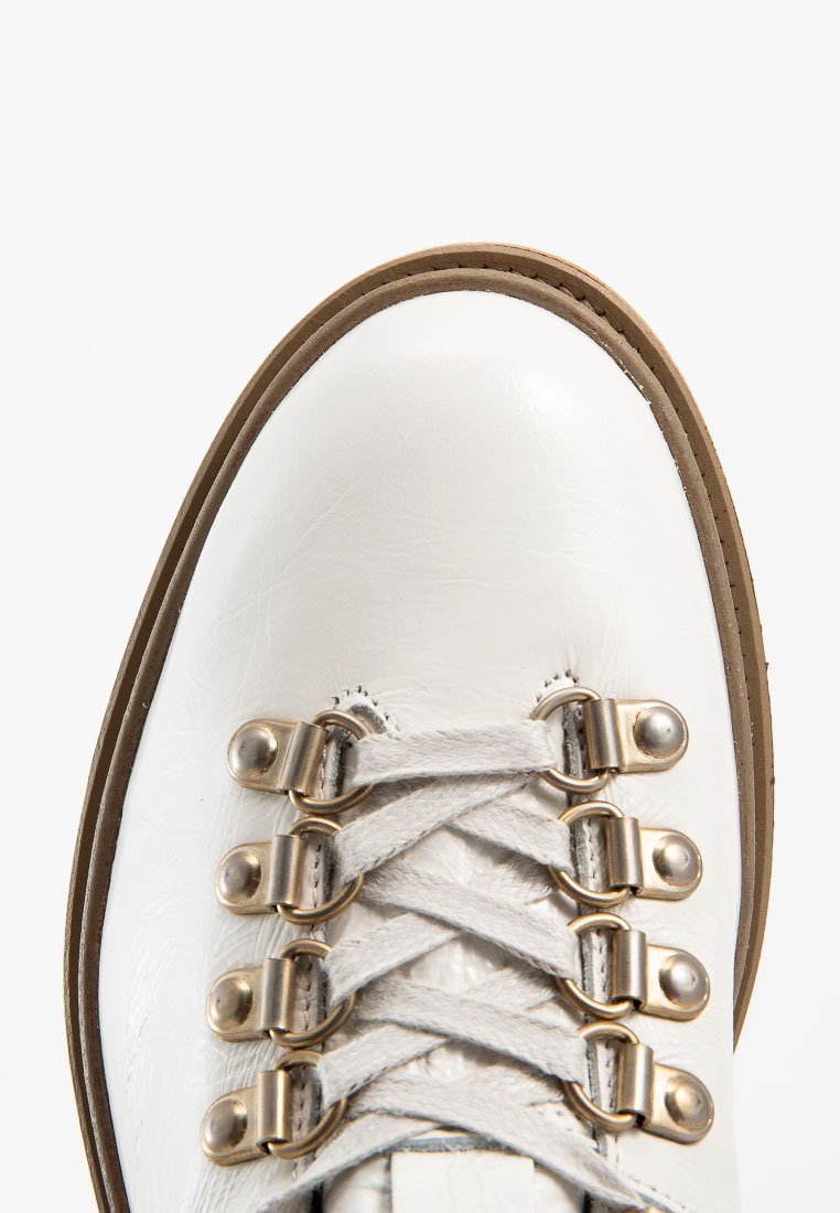 Weißer Lederstiefel mit abgerundetem Zeh, ausgestattet mit Metallösen und grauen Schnürsenkeln. Glatte Oberfläche mit einer beigefarbenen Gummisohle.