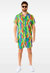 Buntgemustertes Kurzarmhemd und passende Shorts in grünen, blauen, gelben und roten Wellenmustern. Gefertigt aus leichtem, glattem Stoff.