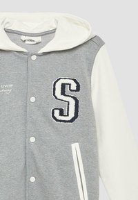 Hoodie gris avec des manches blanches, arborant un "S" brodé en bleu marine sur la poitrine, des boutons-pression et une capuche avec cordon de serrage.