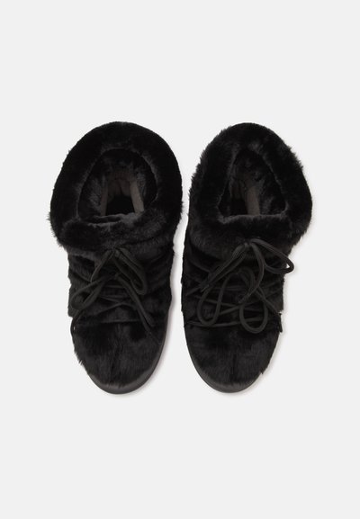 Paire de bottes d'hiver noires recouvertes de fourrure avec des lacets, vues de dessus sur fond blanc.