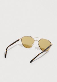 Okulary przeciwsłoneczne z metalową złotą oprawą i żółtymi soczewkami, z zausznikami z octanowego tworzywa z motywem żółwia. Okrągły kształt soczewek z minimalistycznymi elementami metalowymi.