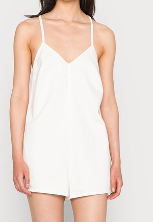 Weißer Leinen-Overall mit V-Ausschnitt, dünnen Trägern und einem lockeren Sitz, mit einem geraden Bein und minimalistischem Stil.