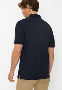 Navy blue polo shirt with short sleeves, side slits at the hem, and a simple collar. Smooth texture, standard fit design.