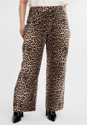 Luipaardprint wijde broek in tan en zwart, gemaakt van een gestructureerde stof. Heeft een hoge taille en zijzakken. Gekleed met zwarte blokhakken.