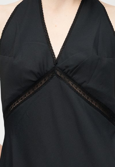 Μαύρο αμάνικο τοπ με V-λαιμόκοψη, δαντέλα κατά μήκος των άκρων και εφαρμοστό μπούστο με λεπτομέρεια ραμμένης υφής στο κέντρο.