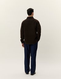 Rjava, teksturirana overshirt s kragnico, nošena čez mornarsko modre hlače. Srajca ima ravno spodnjo rob in dolge rokave.