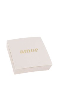 Scatola quadrata di un morbido rosa con una superficie liscia, che presenta la parola "amor" in lettere dorate sulla parte superiore.
