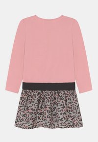 Růžové šaty s dlouhým rukávem, černým pasem a šedou sukní z látky se vzorem růžových a černých leopardích skvrn.