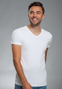 Witte V-hals T-shirt van katoen met korte mouwen, getailleerd ontwerp, zachte textuur, gedragen met casual blauwe spijkerbroek.