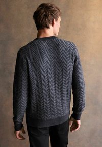 Dunkelgrauer Strickpullover mit Zickzackmuster, gerippten Bündchen und Saum. Von hinten gezeigt, mit rundem Ausschnitt und strukturierter Oberfläche.