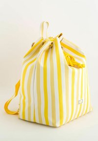 Keltainen ja valkoinen raitapussukka, jossa on litteä pohja, keltainen koristehihna ja pieni logopatch etupuolella.