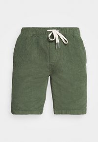 Shorts en coton verts avec une taille élastique, cordon de serrage ajustable et poches latérales. La texture est douce et légèrement texturée.