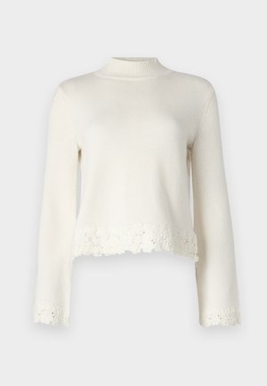 White knitted sweater with long sleeves, high neckline, and scalloped lace trim at the bottom. Soft texture with a cropped design.