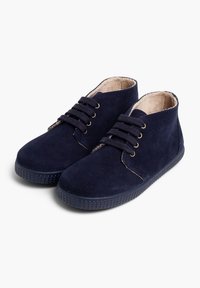 Zapatos de ante azul marino hasta el tobillo con suela de goma texturizada, puntera redonda, seis ojetes y diseño de cordones. Forro interior suave de color claro.