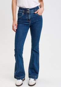 Helleblaue, ausgestellte Jeans aus Denim mit hohem Bund und doppeltem Knopfverschluss, klassischem Fünf-Taschen-Design und subtilen Stitching-Details.