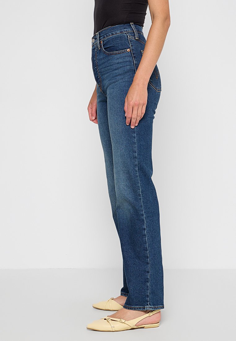 Jeans a vita alta di colore blu scuro con design a gamba dritta, realizzati in denim, dotati di tasche frontali e dettagli di scoloritura leggera.