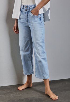 Jasnoniebieskie, skrócone dżinsy o luźnym fasonie, z podwójnym zapięciem na guziki, kieszeniami z przodu oraz lekko strzępionym dołem.