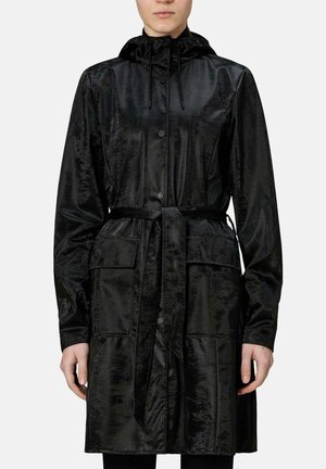 Donna che indossa un cappotto nero con cappuccio, chiusura con bottoni, cintura in vita e grandi tasche frontali, mostrata dal collo a metà coscia.