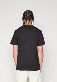 Svart t-shirt med kort ärm och rund halsringning i avslappnad passform. Tyget verkar slätt, utan synliga mönster eller detaljer.