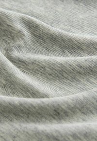 Grauer Strickstoff mit feiner Melierung, weicher Textur und sanftem Fluss sowie sichtbaren Rippen und Dichtevariationen.