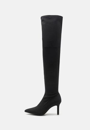 Botte noire cuissarde à talon aiguille avec bout pointu et talon fin, fabriquée en tissu lisse et extensible.