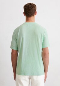Mintgrünes T-Shirt aus leichtem Stoff, mit rundem Halsausschnitt und kurzen Ärmeln, sowie einer dezenten Textur.