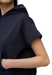 Sudadera corta de color azul marino, hecha de una tela suave, presenta una gran capucha, mangas cortas y un bolsillo delantero. Logo "Marc O'Polo" cerca de la capucha.