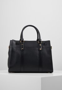 Borsa a mano in pelle nera con superficie texturizzata, doppi manici arrotondati, dettagli in metallo dorato e design strutturato.