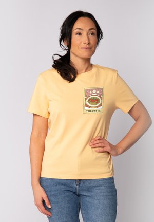 T-shirt en coton jaune avec un design graphique à l'avant représentant des pâtes dans un bol entouré d'étoiles, encadré, et le texte "LES PÂTES". Manches courtes.