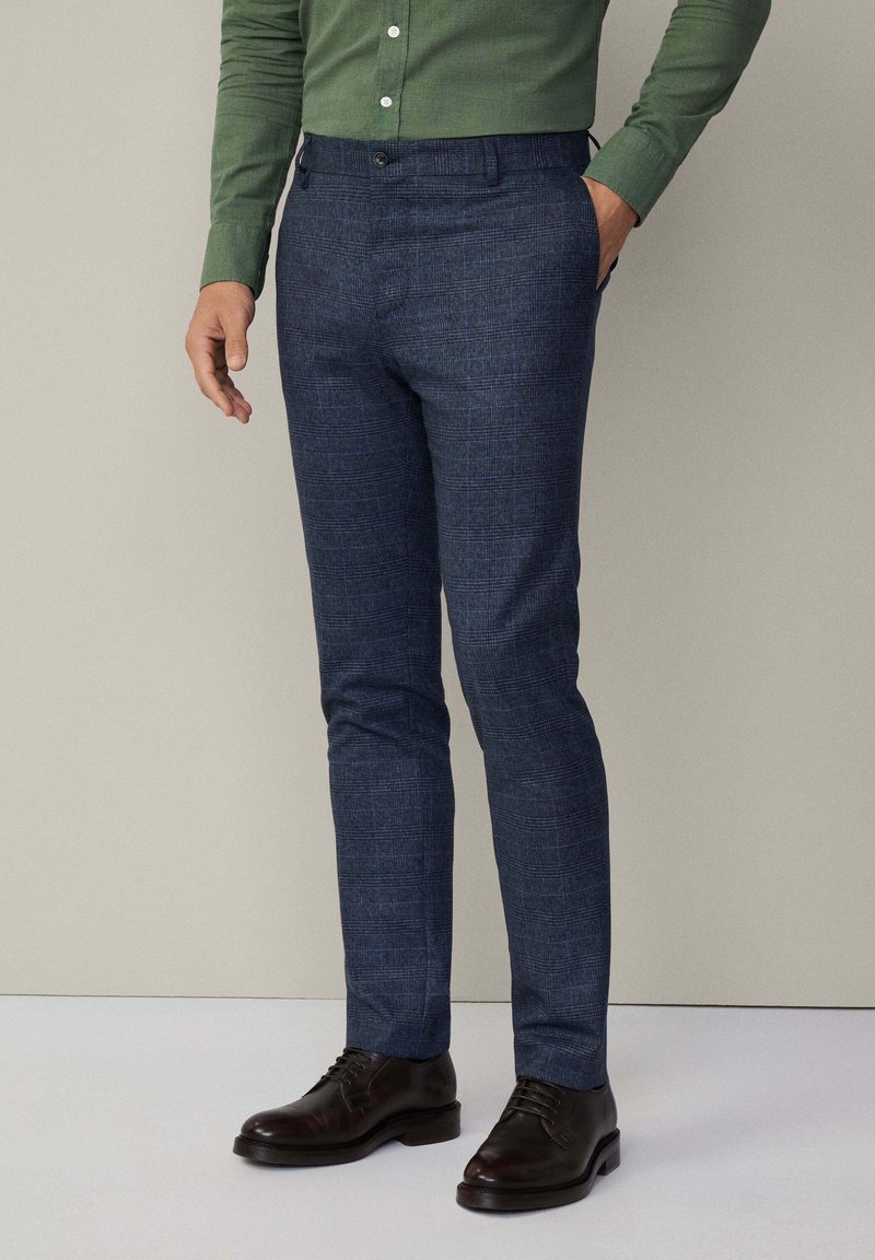 Op maat gemaakte broeken van donkerblauwe stof met een gestructureerd patroon, met een rechte pasvorm, riemlussen en een sluiting met een knoop aan de voorkant.