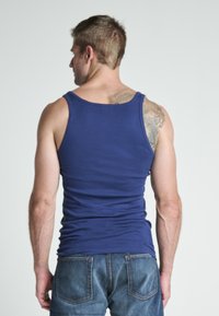 Top in cotone blu navy con design aderente, scollatura rotonda e senza maniche, mostrato da dietro, abbinato a jeans blu.