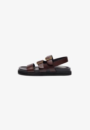 Sandales en cuir marron au design minimaliste, avec deux sangles réglables et une sangle arrière. Elles ont une semelle en caoutchouc noir pour une meilleure adhérence.