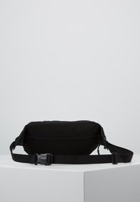 Svart stoff fanny pack med glidelås, justerbar stropp, flat design og glatt tekstur. Egnet for uformell bruk og bekvemmelighet.