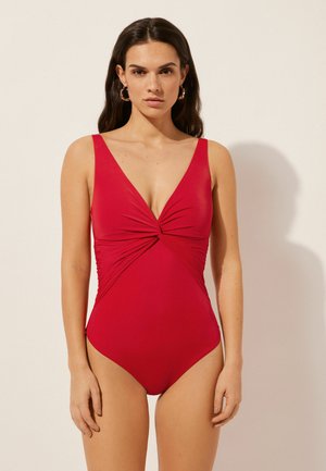 Maillot de bain une pièce rouge avec un décolleté en V profond, un design à l'avant torsadé et des détails froncés sur les côtés. Tissu lisse, style minimaliste et sans matériel visible.