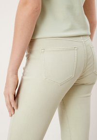 Ljust gröna denimjeans med en figursydd design. Funktioner inkluderar en medelhög midja, två bakfickor och kontrasterande sömdetaljer.