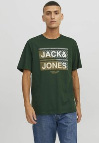 Donkergroene katoenen T-shirt met een gedurfde grafische print met de tekst "JACK & JONES" in wit, grijs en goud, korte mouwen en een ontspannen pasvorm.