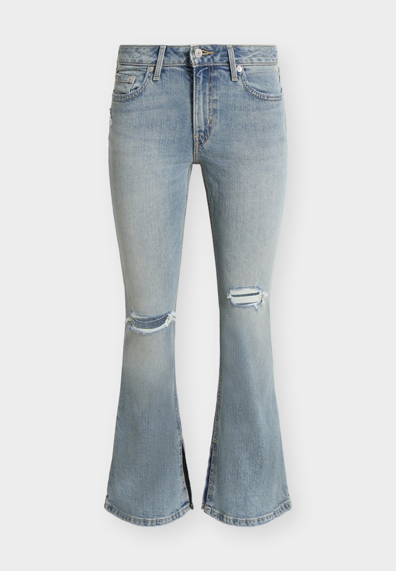 Jean flare bleu clair délavé avec déchirures aux genoux et fentes à l'avant, muni d'une fermeture par bouton et fermeture éclair ainsi que d'un design à cinq poches.