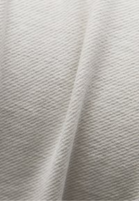 Tissu textile gris clair avec un tissage texturé et côtelé. La surface présente des variations subtiles de nuances et une apparence douce et uniforme.