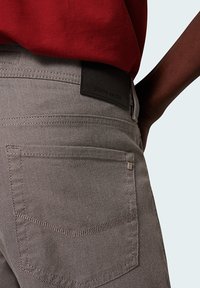 Gray textured pants with a leather tag embossed "pierre cardin," featuring a back pocket and subtle stitching details.