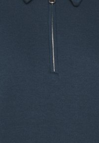 Maglia a mezza zip blu navy realizzata in tessuto a maglia con una texture liscia. Presenta un colletto classico e una zip metallica lucida.