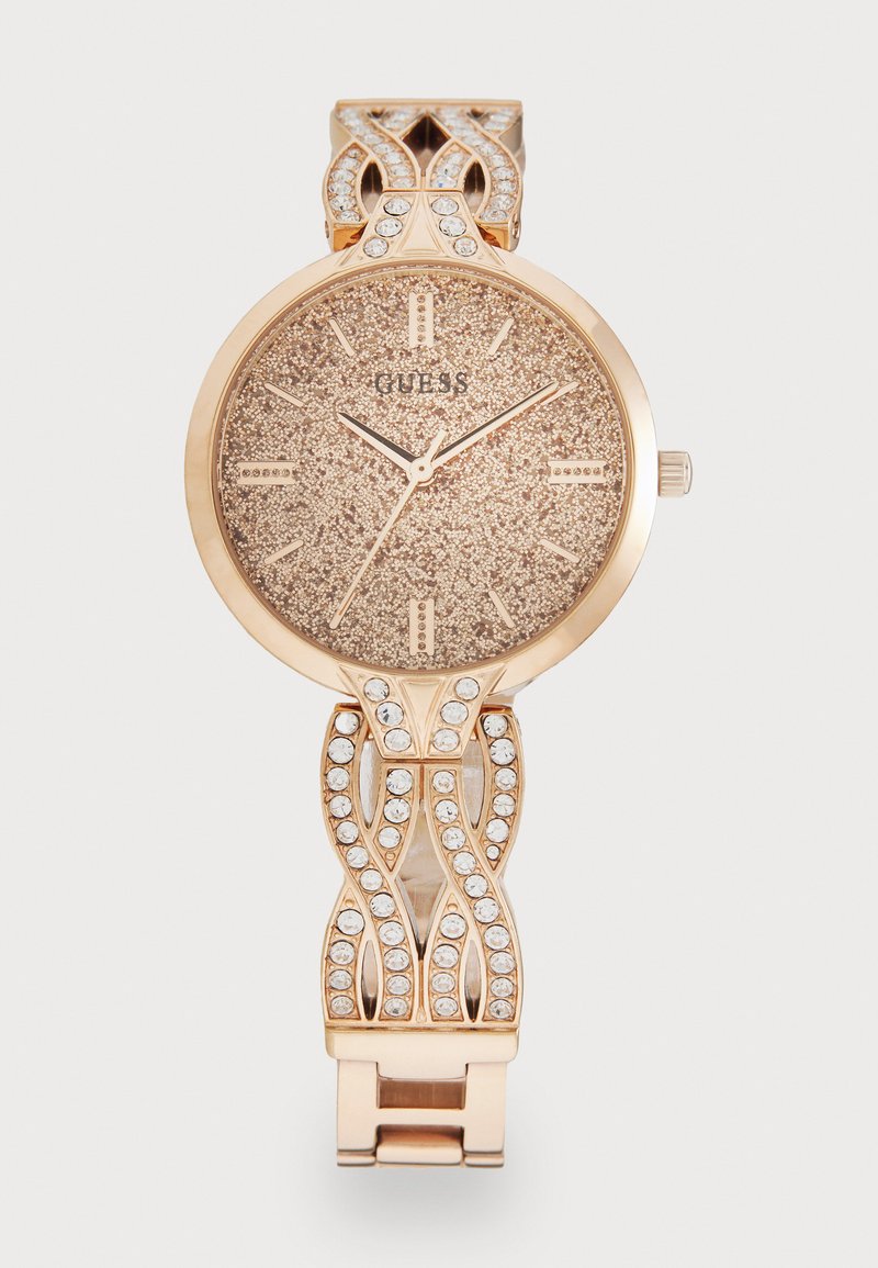 Orologio in oro rosa con quadrante scintillante, dettagli argentati e bracciale decorativo adornato da cristalli trasparenti e un design ondulato.